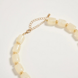 neutral chunky beaded necklace with large gold seashell pendant