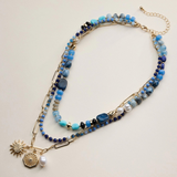 blue layered beaded and chain necklace with sun and pearl charms