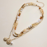 neutral layered beaded and chain necklace with sun and pearl charms