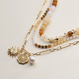 neutral layered beaded and chain necklace with sun and pearl charms